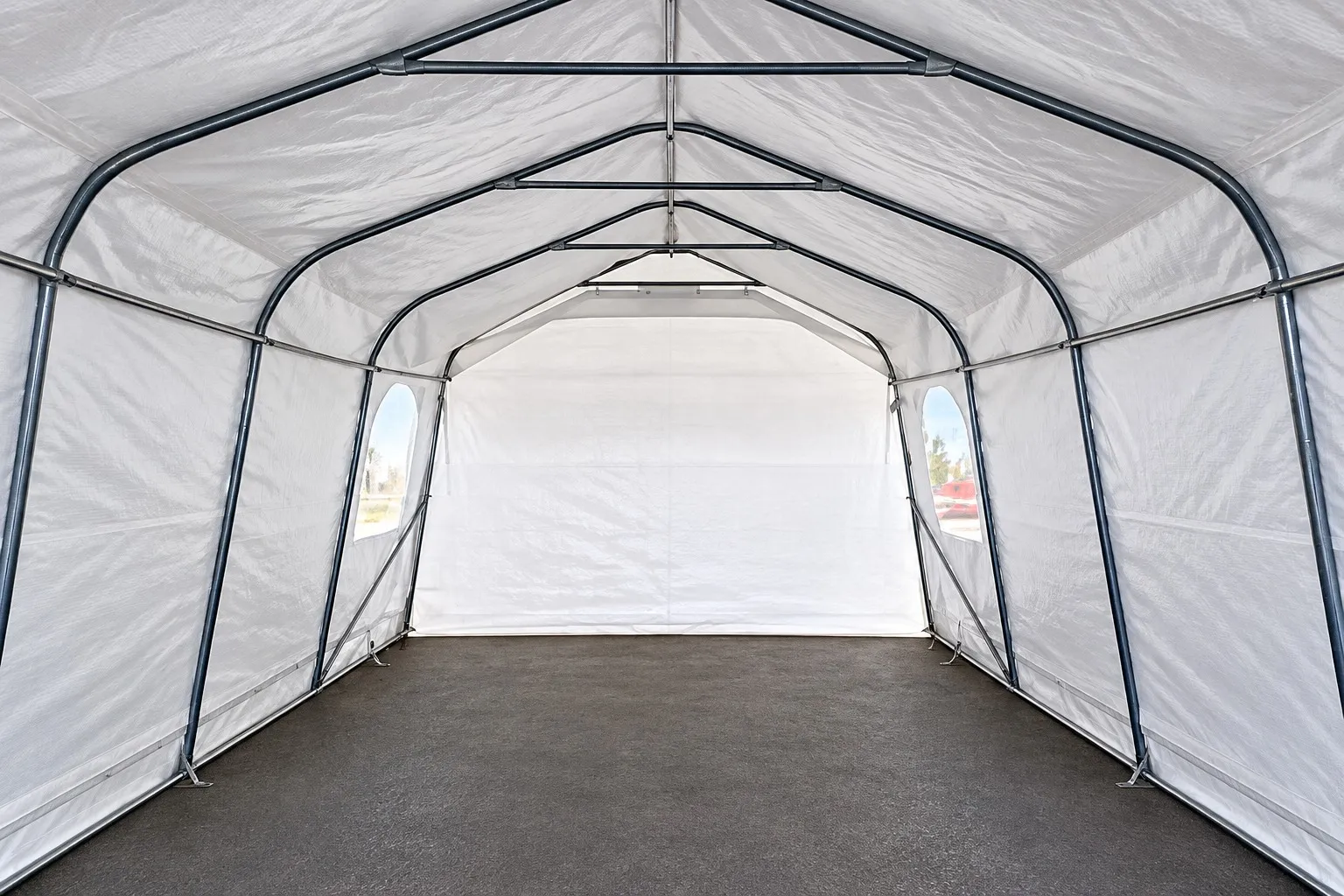 Intérieur d'un abri : arches en acier reliées par des traverses, sous une toile blanche.